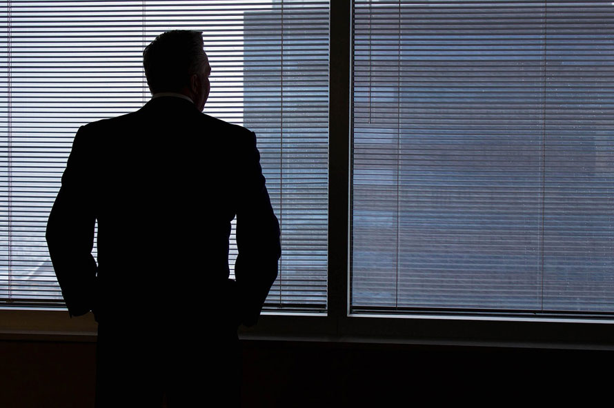 Business man alone looking out office window